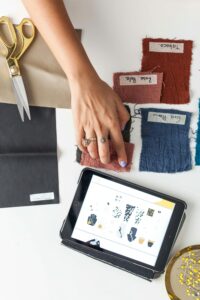 Designer arranging textile swatches and using a tablet for fashion design ideas.